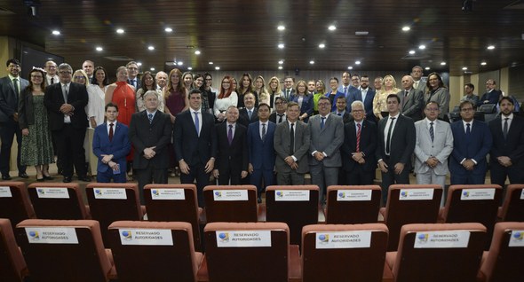 #PraTodosVerem: Na fotografia aparecem um auditório, com pessoas em pé, e, ao fundo, mesa de tra...