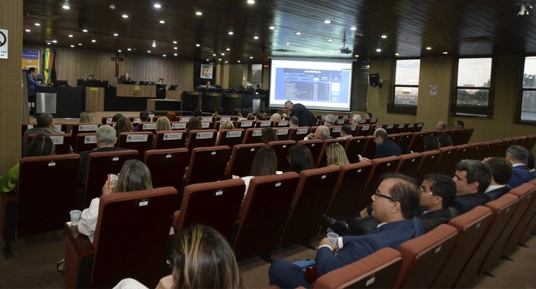 #PraTodosVerem: Na fotografia aparecem um auditório, com pessoas sentadas, e, ao fundo, mesa de ...