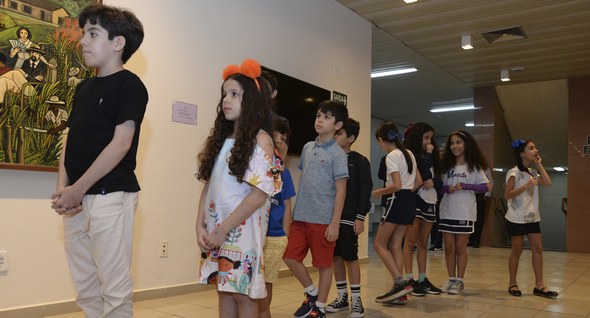 #PraTodosVerem: Na fotografia aparece crianças em uma fila, ao fundo uma mesa com uma urna eletr...