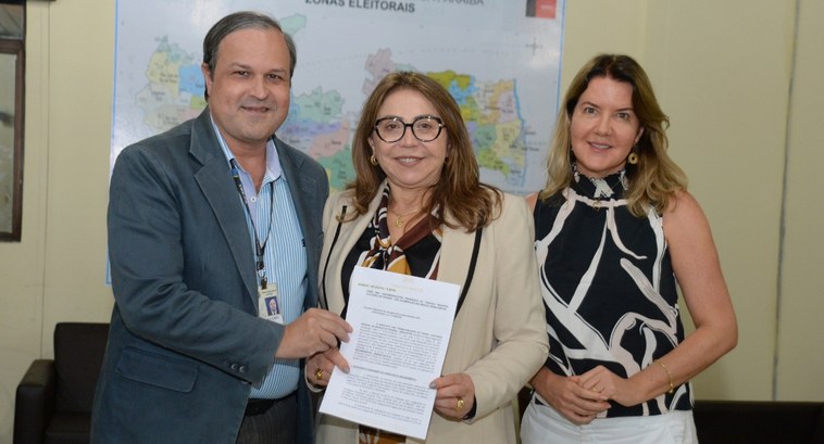 #PraTodosVerem: Na fotografia aparecem um homem e duas mulheres, em pé, posando, na sala da Pres...