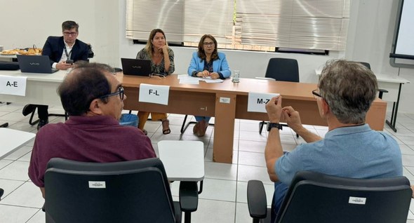 #PraTodosVerem: Na foto aparecem pessoas sentadas e em um auditório e, ao fundo, uma mesa de tra...