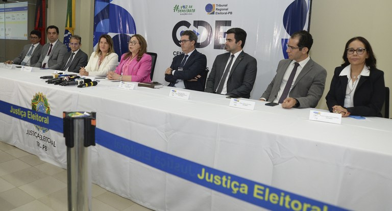 Painel retangular muitas pessoas sentadas à mesa, homens e mulheres