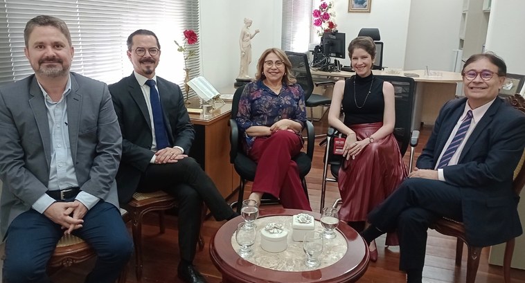 #PraTodosVerem: Na foto, imagem de pessoas reunidas em uma sala, sendo duas mulheres e três homens