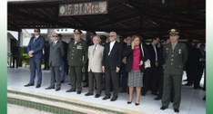 #ParaTodosVerem: Painel retangular com várias pessoas de pé, assistindo ao desfile militar.